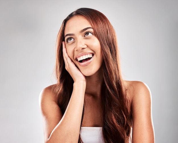 El pensamiento del cabello y la mujer en el estudio para el cuidado de la belleza y el tratamiento de salón sobre fondo gris.