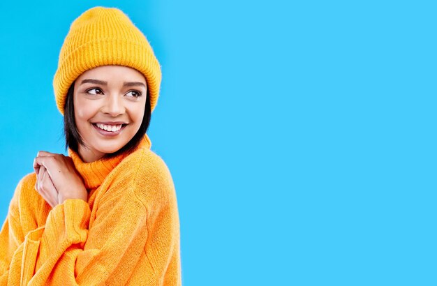 Foto pensamiento de felicidad y mujer con moda y maqueta en estudio en clima frío con sombrero de invierno fondo azul aislado y maqueta con un joven feliz y una persona de la generación z con un gorro de sonrisa y alegría