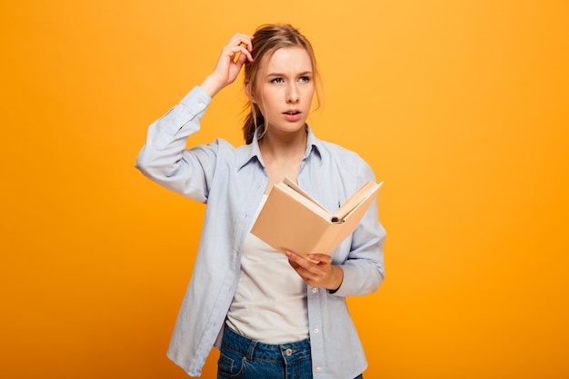 Pensamiento serio joven estudiante leyendo libro.