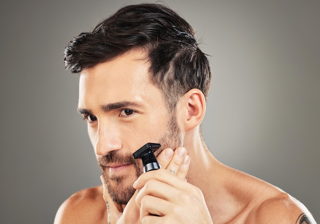 Pensando en afeitarse y un hombre con una maquinilla de afeitar para el cuidado de la piel y la belleza de la cara contra un fondo gris de estudio Cosmético limpio y un hombre con una idea para el vello facial saludable de la barba y la salud de la piel