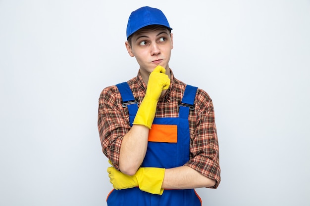 Pensando agarrou o queixo jovem cara de limpeza vestindo uniforme e boné com luvas