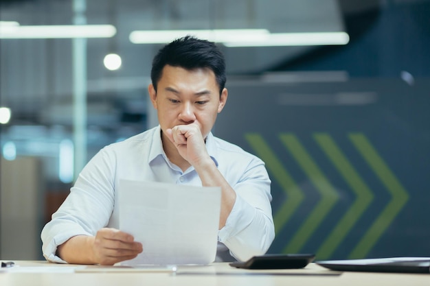 Pensando en un hombre de negocios asiático que trabaja en la oficina con documentos hombre pensando y leyendo una carta del banco