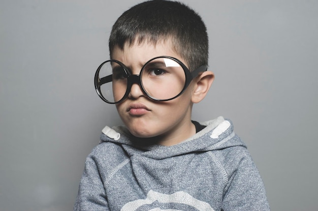 pensando, menino com óculos grandes muito sério e pensando