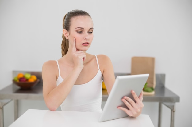 Pensando en mujer joven usando su tableta en la mesa