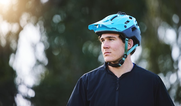 Pensando na natureza e um homem com um capacete para treinamento de ciclismo para um triatlo ou uma ideia esportiva Foco no condicionamento físico e um ciclista ou atleta masculino com visão para uma viagem de maratona ou treino de cardio
