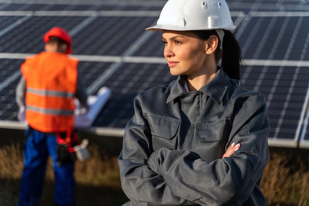 Una pensativa especialista en técnicas industriales caucásicas con cruzar la mano cerca de las baterías de energía