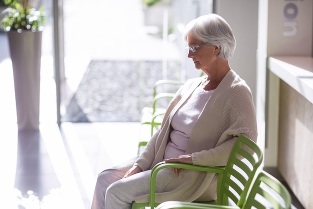 Pensativa mulher idosa sentada na cadeira