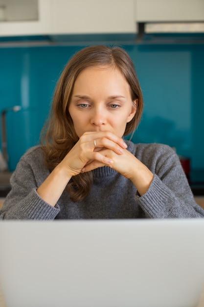 Pensativa senhora bonita trabalhando no laptop em casa