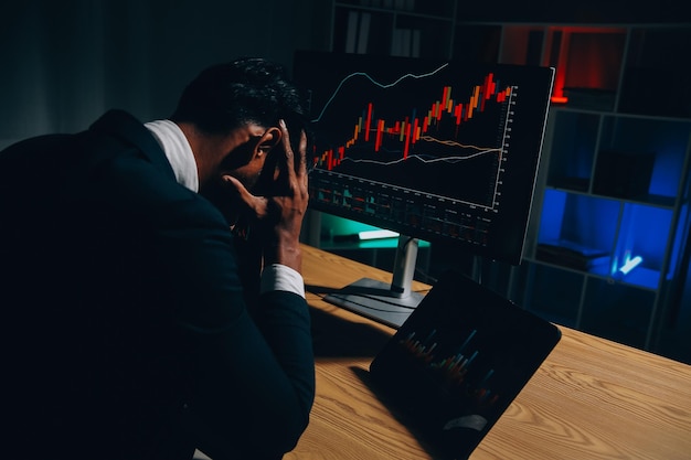 Pensativo, enfocado, exitoso, hombre caucásico, inversor bursátil, corredor, asesor financiero, se sienta en su escritorio de trabajo, mira la computadora, analiza pensativamente los riesgos y las perspectivas, sube o baja la moneda de criptomoneda.