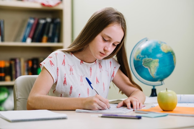 Pensativo estudiante niña escrito