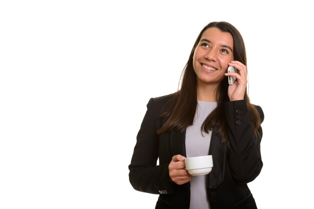 Pensativo feliz empresaria caucásica sonriendo y hablando por teléfono móvil mientras sostiene la taza de café