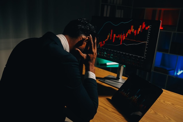 Pensativo, focado, bem sucedido, homem caucasiano, investidor de ações, corretor, conselheiro financeiro, senta-se na mesa de trabalho, olha para o computador, analisa pensativamente os riscos e as perspectivas, a ascensão ou queda da moeda de criptomoeda.
