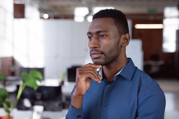 Pensativo hombre de negocios afroamericano de pie en el cargo mirando hacia otro lado. trabajar en negocios en una oficina moderna.