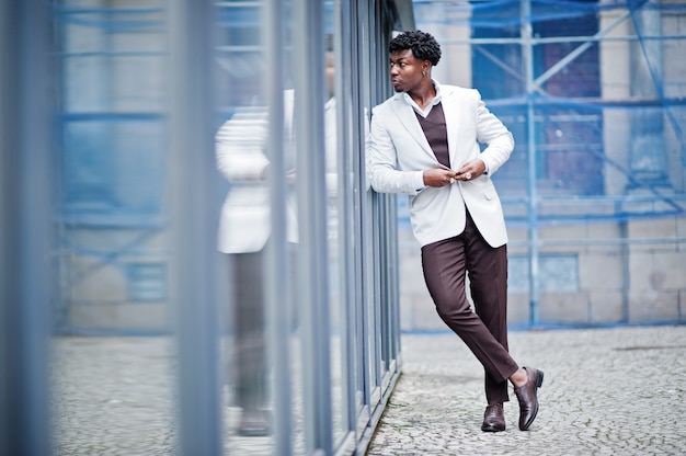 Pensativo jovem bonito cavalheiro americano africano em trajes formais. homem preto elegante modelo de jaqueta branca.