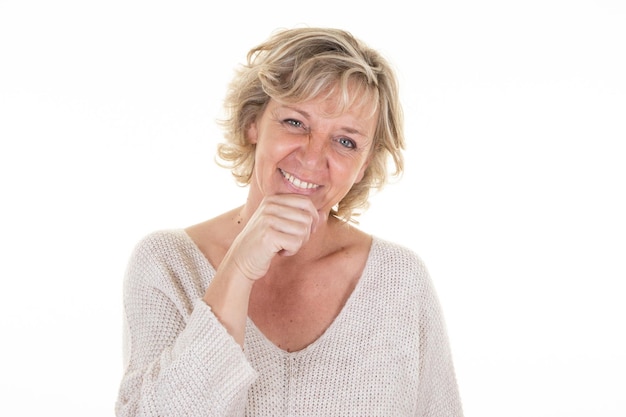 Pensativo de mediana edad hermosa mujer senior rubia sonriente mano sobre la barbilla posando en fondo blanco.