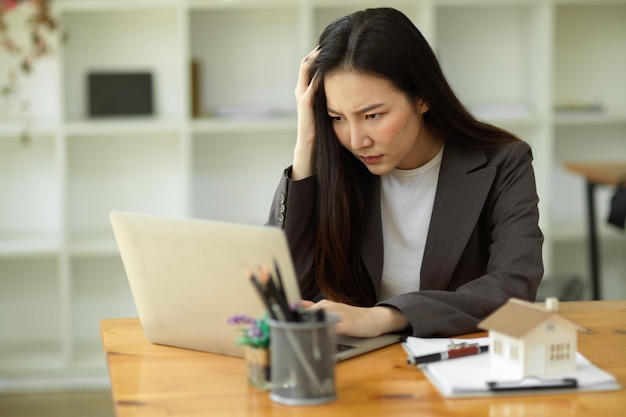 Pensativo reflexivo serio reflexionar joven empresaria asiática trabajando en su computadora portátil en la oficina