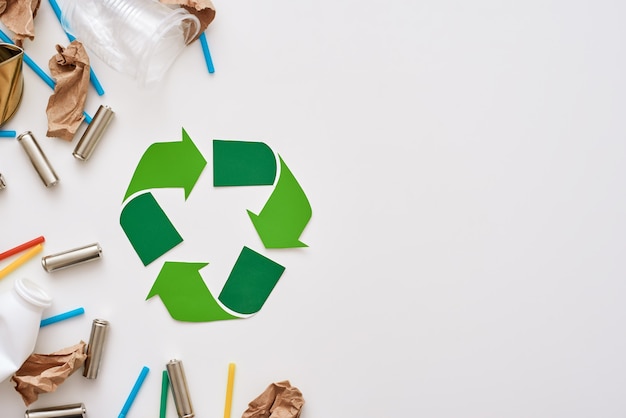 Pense em ecologia. Papel amassado, plástico e baterias estão do lado esquerdo do símbolo de reciclagem. Diferentes tipos de lixo não classificado