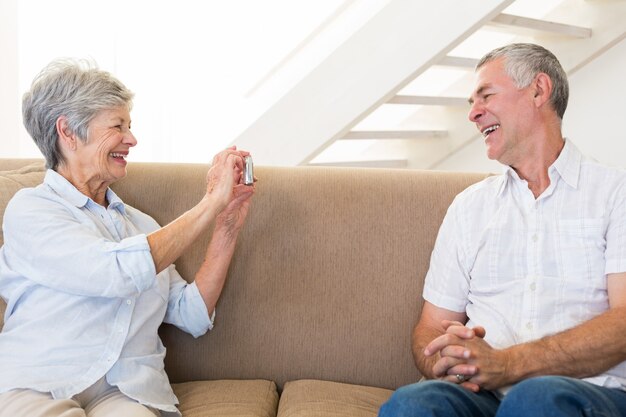 Pensionierte Frau, die Foto ihres Partners auf der Couch macht