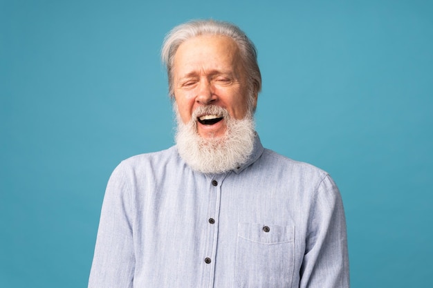 Pensionierter alter Mann mit weißem Haar und Bart, offenem Mundlachen aufgeregt über blauem Hintergrund