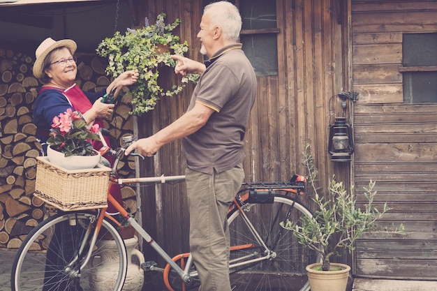 pensioniertes erwachsenes kaukasisches paar bleiben im garten in seinem eigenen haus, um an den pflanzen und gemüse zu arbeiten. Fahrrad im alten Stil mit ihnen