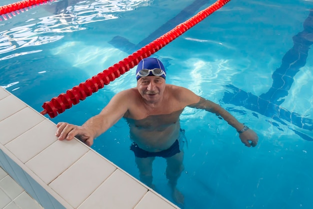 Un pensionista de 70 años descansa nadando recuperándose en la piscina con agua clara y azul en el hotel