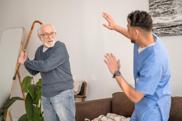 Foto pensionista agresivo blandiendo el bastón a su cuidador