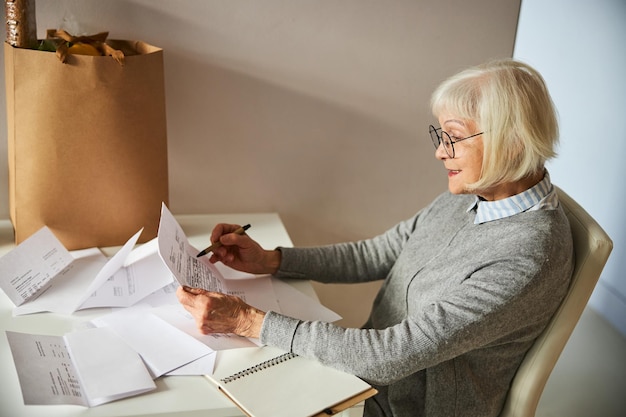 Pensionista enfocado en anteojos leyendo un documento