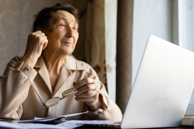 Pensionista lee innumerables trabajos y está muy concentrado. mujer mayor cálculo de impuestos en casa. mujer jubilada calculando sus facturas domésticas. concepto de negocio, ahorros, seguro de anualidad, edad y personas