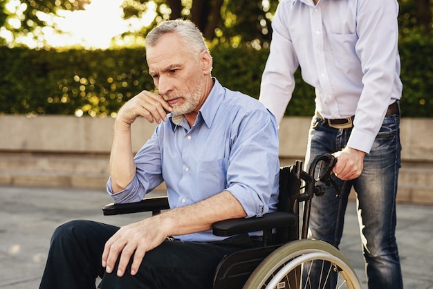 Pensionista triste em cadeira de rodas. Preocupe-se com os deficientes.