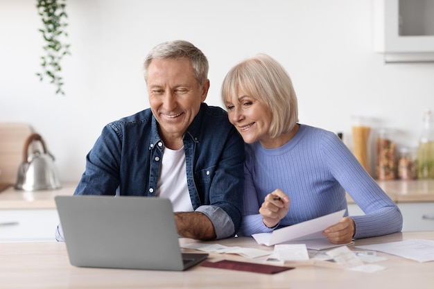 Foto pensionistas felices sentados frente a la computadora leyendo correos electrónicos