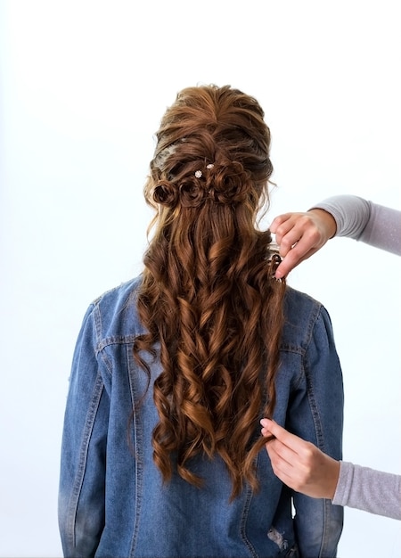 Penteado de cachos ondulados. cabeleireiro fazendo penteado para mulher de cabelo castanho-ruivo com cabelo comprido usando pente