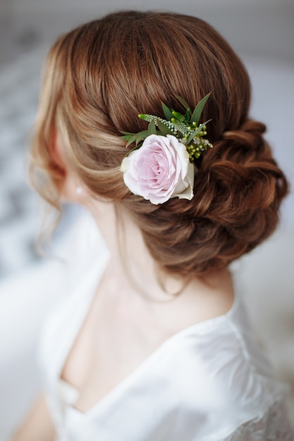 Penteado de jovem linda noiva com flores frescas.