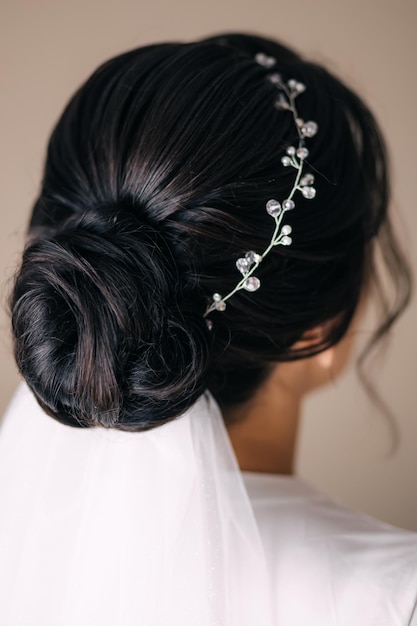 Penteado para casamento com véu A noiva fica de costas para a câmera Trançando enfeites de diadema de cabelo Preparação para a cerimônia Manhã da noiva