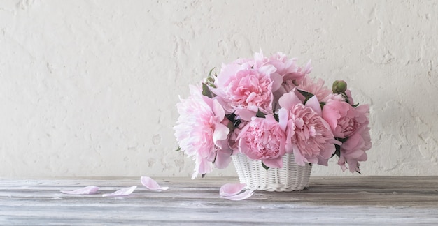 Peonía rosa en el canasto sobre fondo de pared vieja