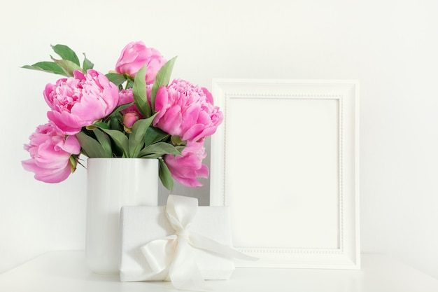 Peônia rosa em um vaso com moldura de presente em branco.