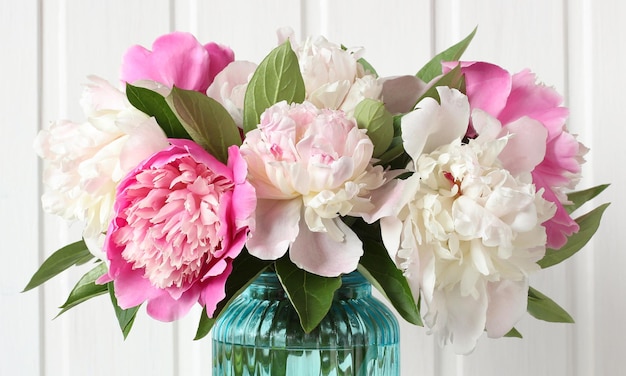 Peônias rosa e brancas como fundo natural, um buquê em close-up, flores em um vaso de vidro azul