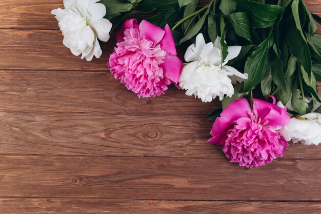 Peonías rosas y blancas sobre un fondo de madera