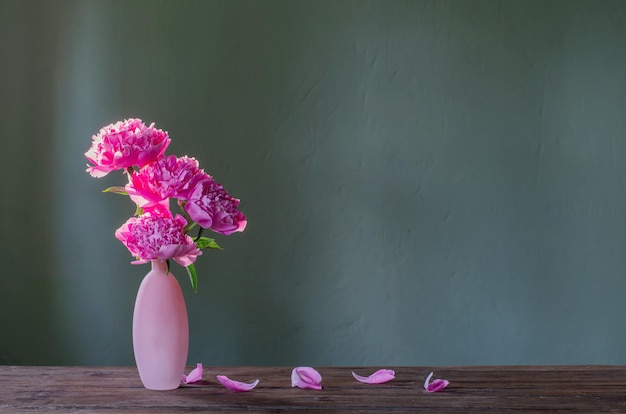 Peonías rosas en jarrón rosa sobre fondo verde