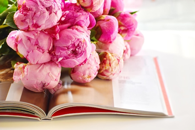 Peonías rosas y libro Leyendo su libro favorito Fondo de flores Las flores se encuentran en un libro abierto