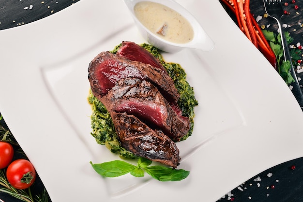 Peper Kalbssteak mit Spinat auf einem hölzernen Hintergrund Ansicht von oben Kopieren Sie Platz