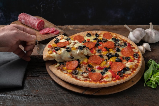 Foto peperoni-pizza auf einem holztisch mit einem grauen tuch, knoblauchbasilikum und salami