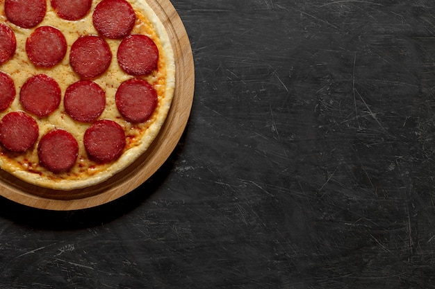 Peperoni-Pizza Italienisch gekocht ganz ungeschnitten Draufsicht dunkler Hintergrund mit Platz zum Kopieren von Text