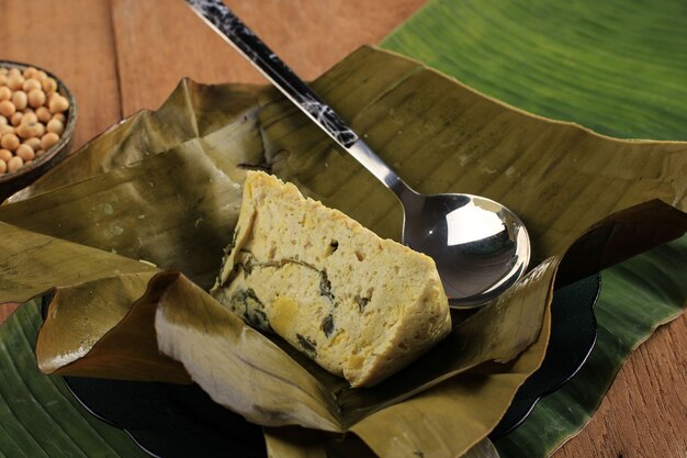 Pepes Tahu es tofu especiado de Indonesia envuelto con hoja de plátano y cocido al vapor, comida típicamente indonesia de Java Occidental (Sundanés). Tofu al vapor con albahaca asiática, de cerca