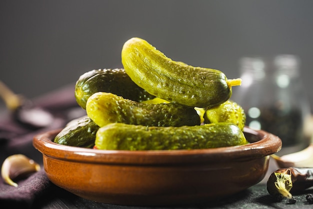 Pepinillos en escabeche. Pepinos salados sobre un fondo rústico oscuro, vertcal