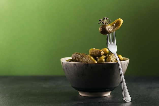 Pepinillos, pepino encurtido en un tenedor, plato de verduras marinadas en un verde