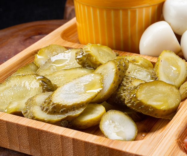 Pepino encurtido en rodajas sobre tabla de madera.