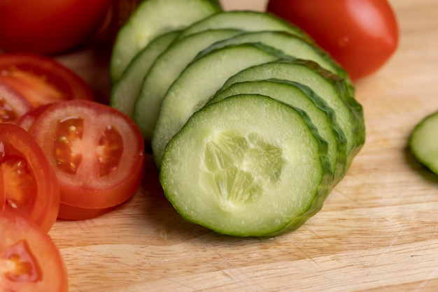 Pepino largo verde en rodajas durante la preparación de la ensalada preparación de ensalada con verduras cortadas en trozos pequeños de pepinos verdes