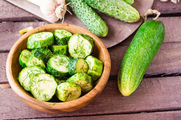 Pepino recién salado en vinagre con ajo y eneldo en un plato de madera