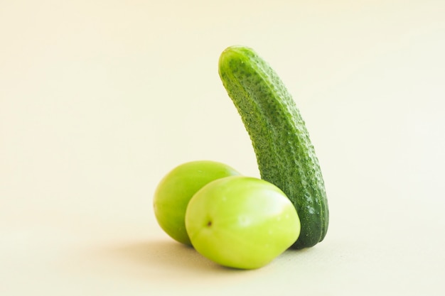 Pepino verde y dos tomates verdes sobre un fondo beige. concepto de pene masculino.