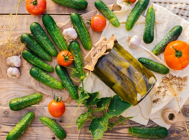 Pepinos em conserva salgados em uma jarra em uma mesa de madeira no jardim Pepinos tomates ervas endro alho Conservação de preservação Espaço de cópia de fundoVista superior